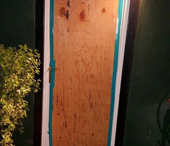 Image shows a boarded up exterior door that was broken into